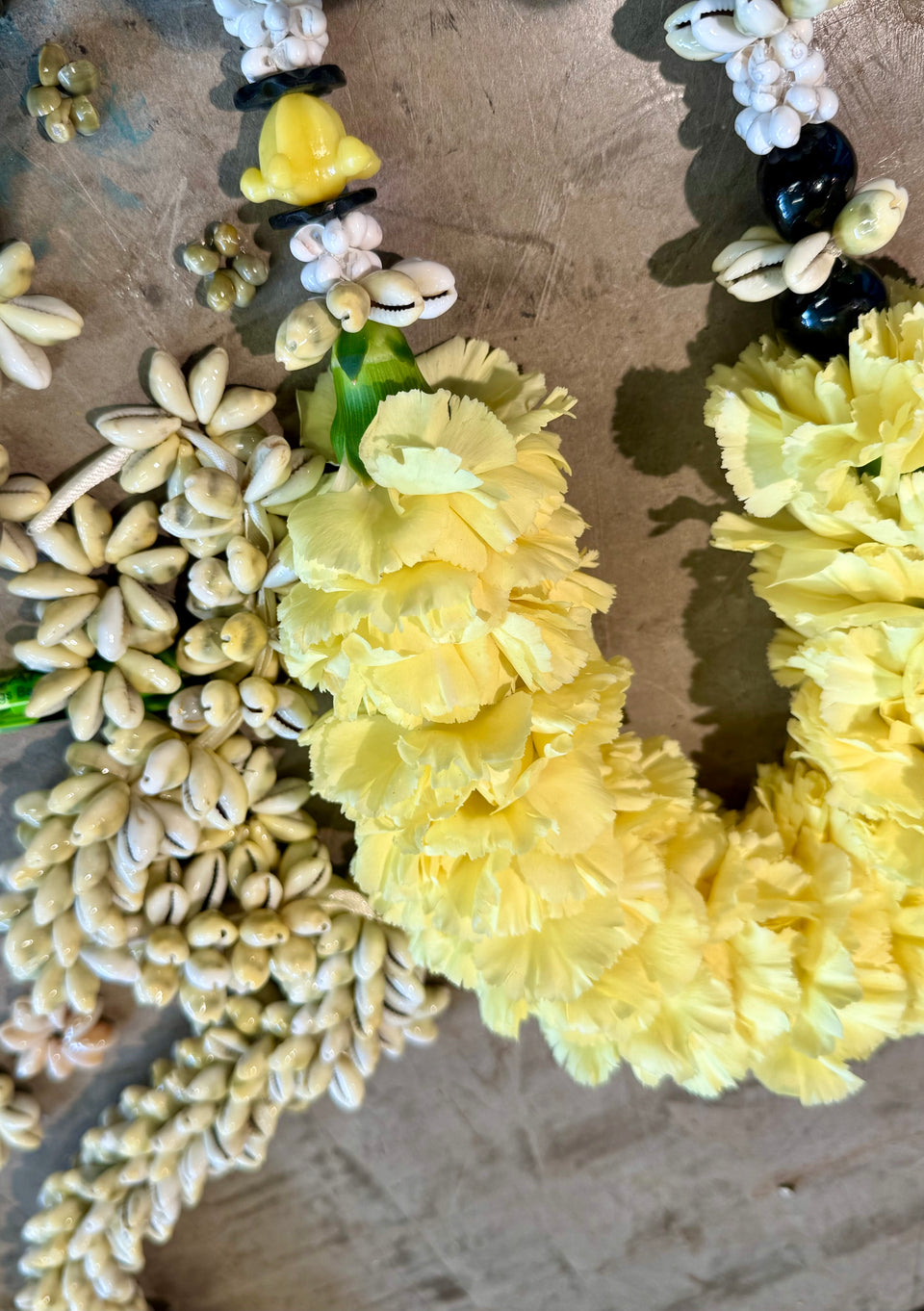 Carnation flower lei with shells and beads on a table