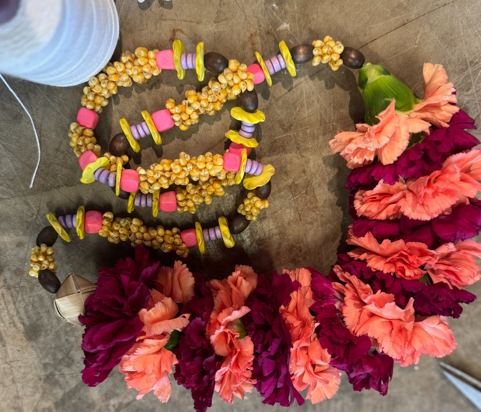 Stripped carnation lei on table in process of being made