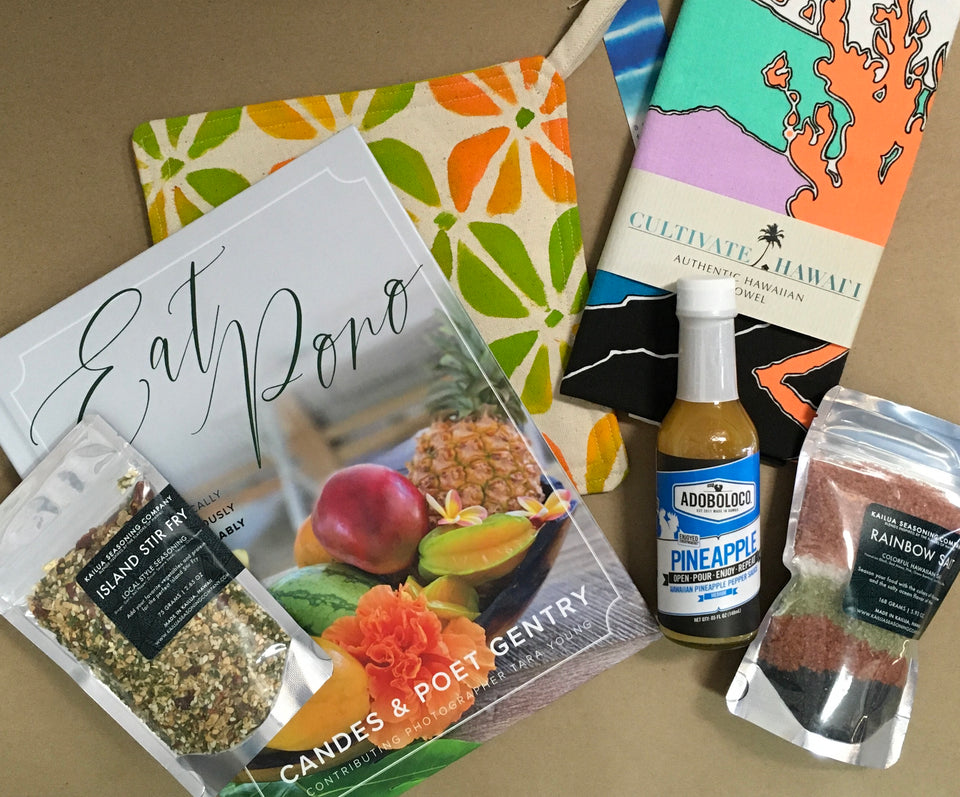 contents of basket - dishtowel, spices, hot sauce, cook book and hot mit all made in hawaii