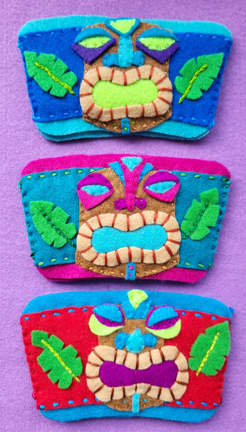 three multi colored hand stitched tiki cup covers made in hawaii of felt
