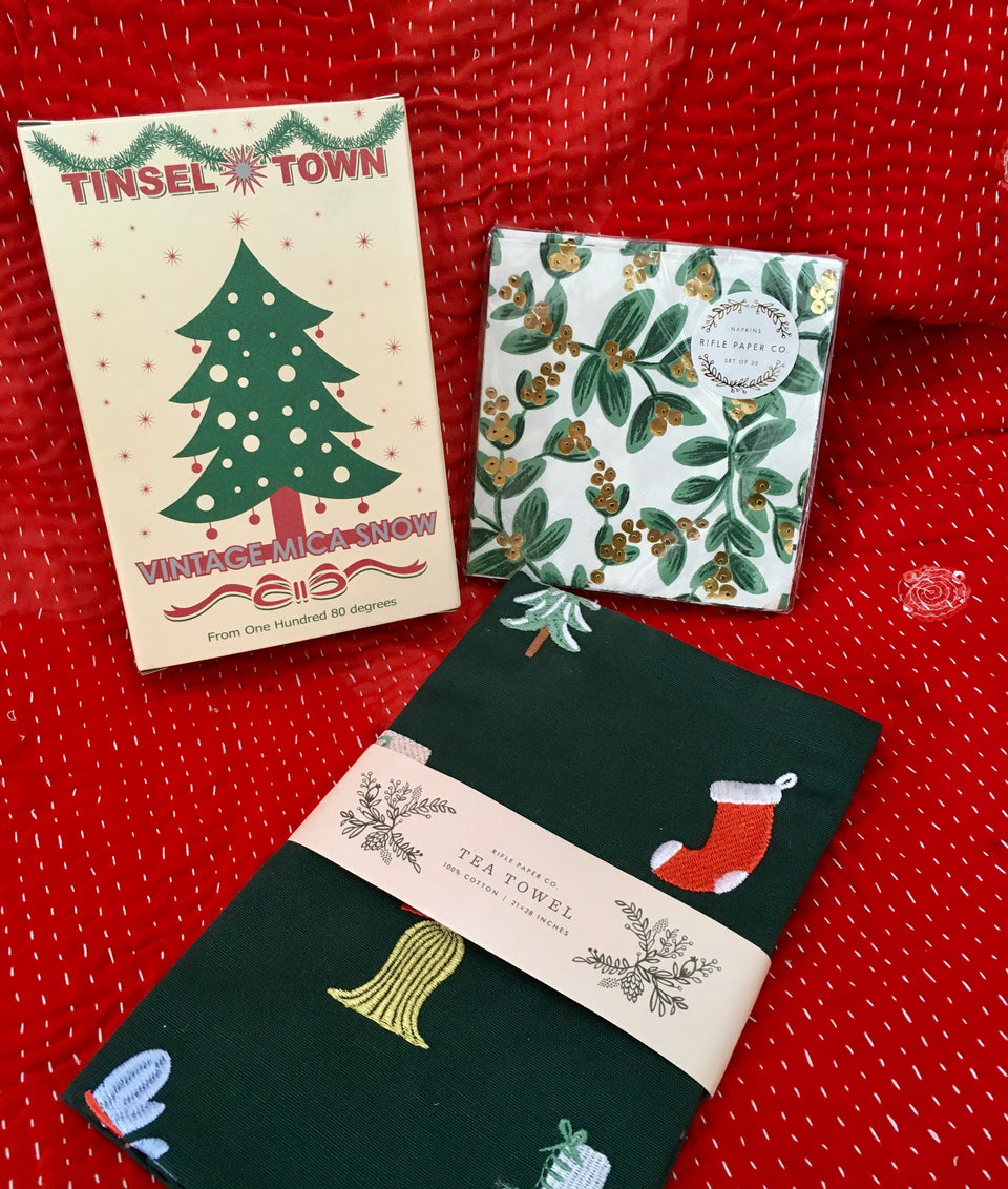 shows package of tinsel, pack of holiday napkins and holiday tea towel