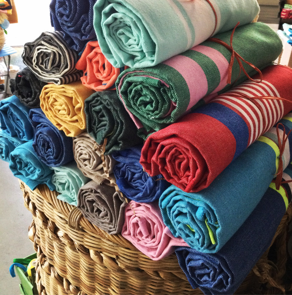 Shows a pyramid of rolled up Turkish towels to show the variety of colors they come in