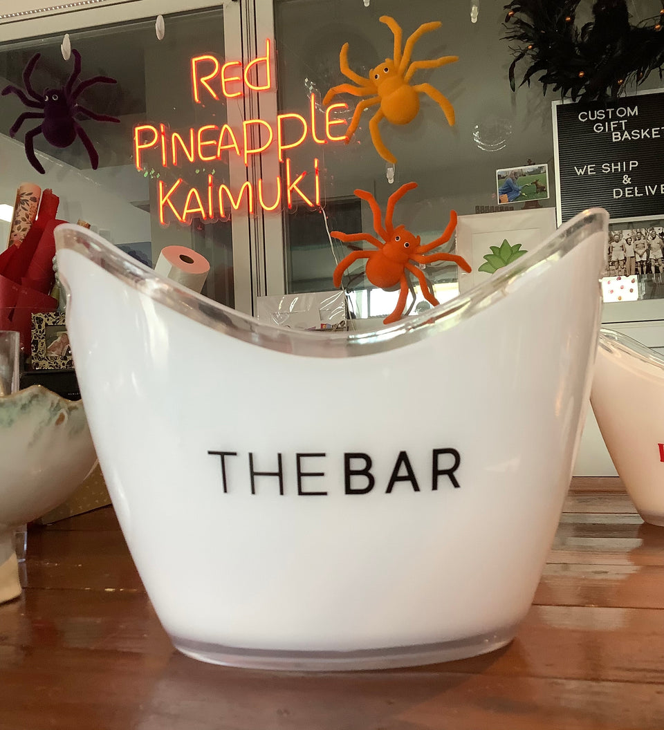 White acrylic ice bucket with black lettering that says the bar