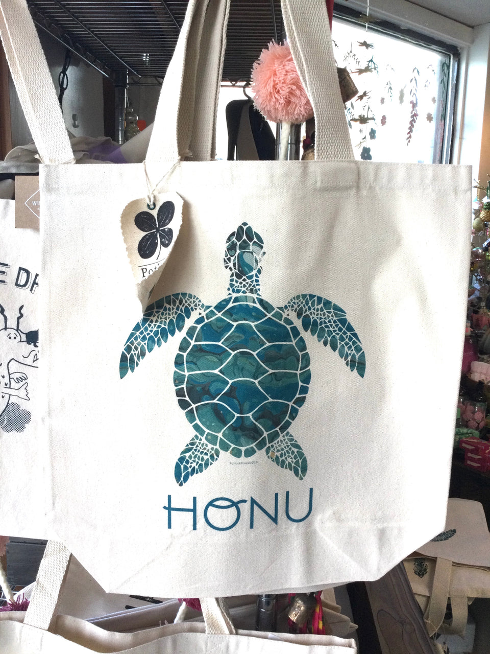 Canvas tote bag with turtle mosaic design in teal with the word Honu below