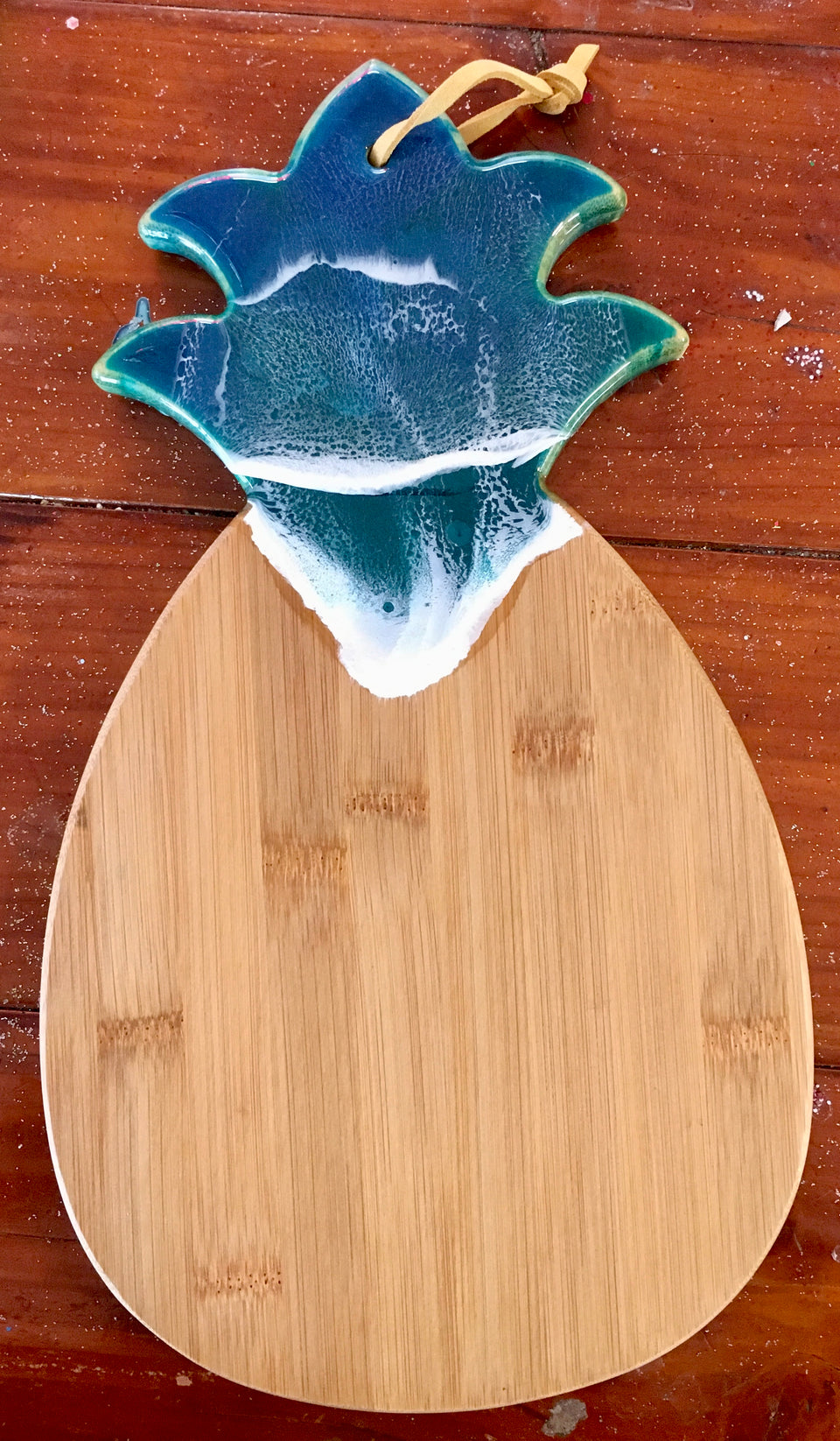 wooden cutting board in the shape of a pineapple with ocean wave resin at the top.