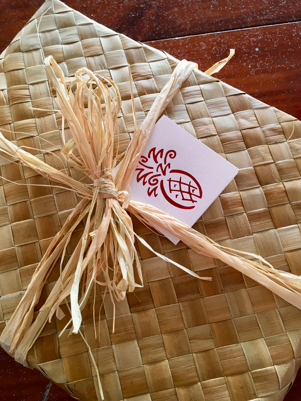 lauhala gift basket tied with raffia and red pineapple card