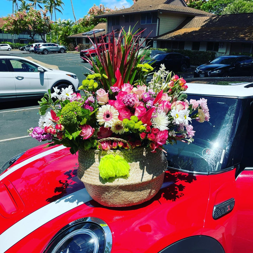 Huge basket of mixed blooms on the top of a car