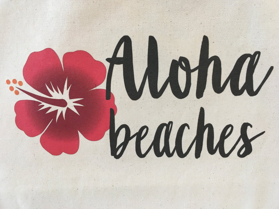Close up detail. Aloha Beaches printed in black and a red hibiscus.