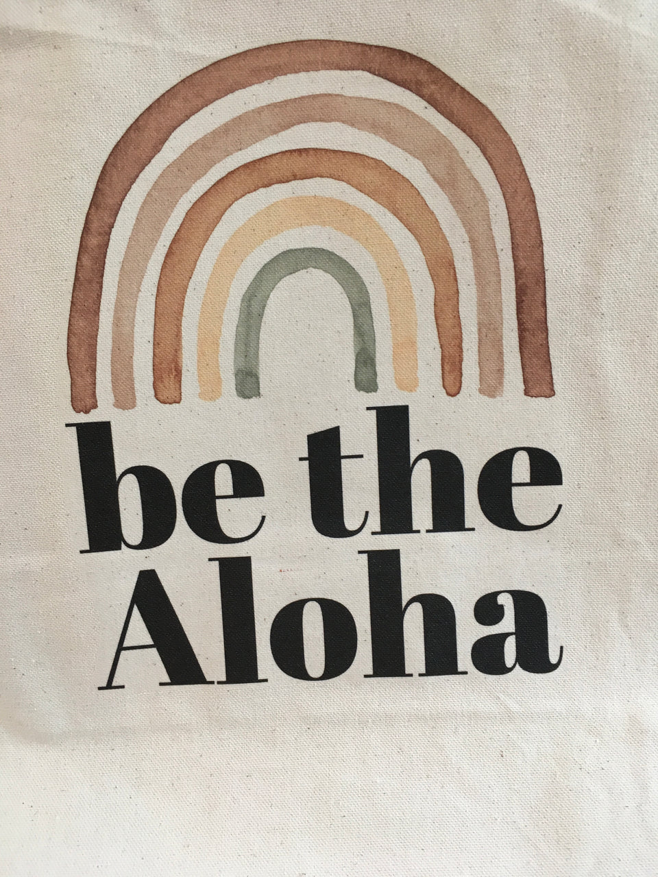 Large canvas bag with earth tone rainbow and be the aloha written in black font.