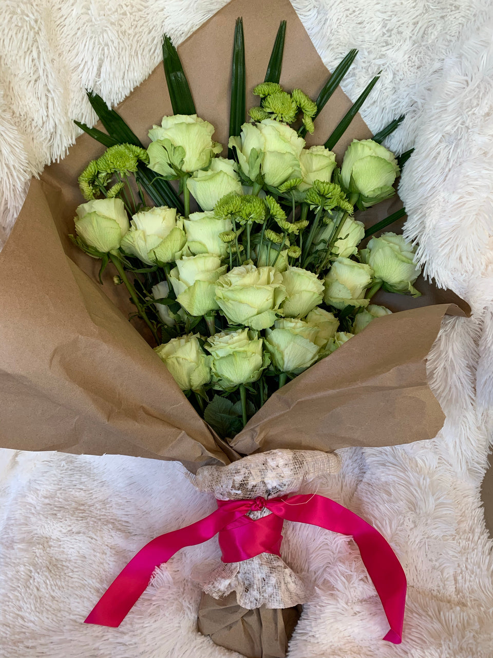 bundle of green roses and green blooms tied into brown paper