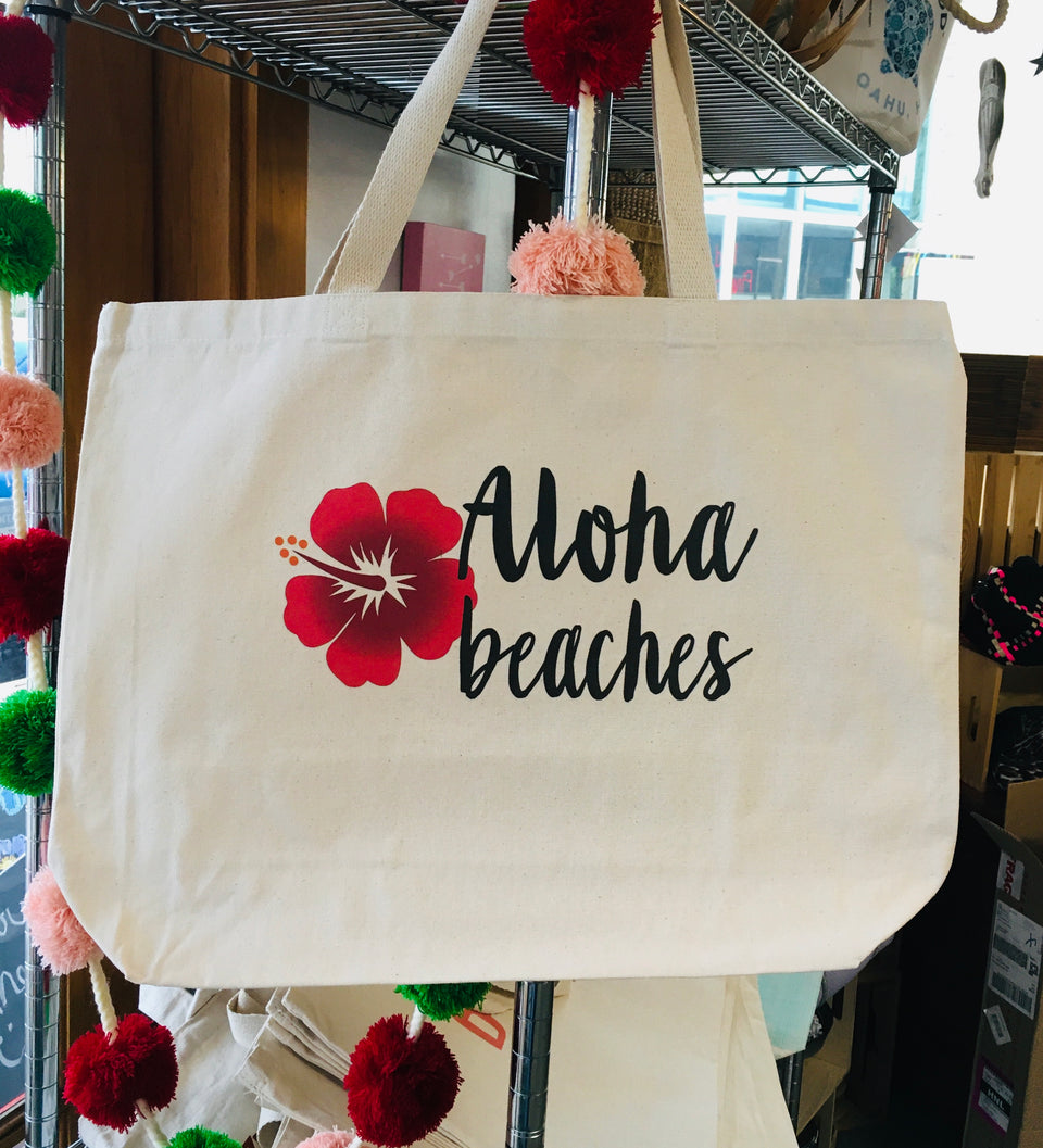 Large canvas tote with Aloha Beaches printed in black and a red hibiscus.