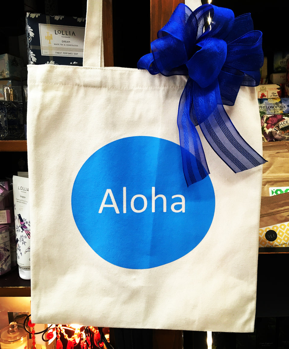 canvas bag with blue cirlce and the word aloha in the middle. bag also has a blue  bow on one side.