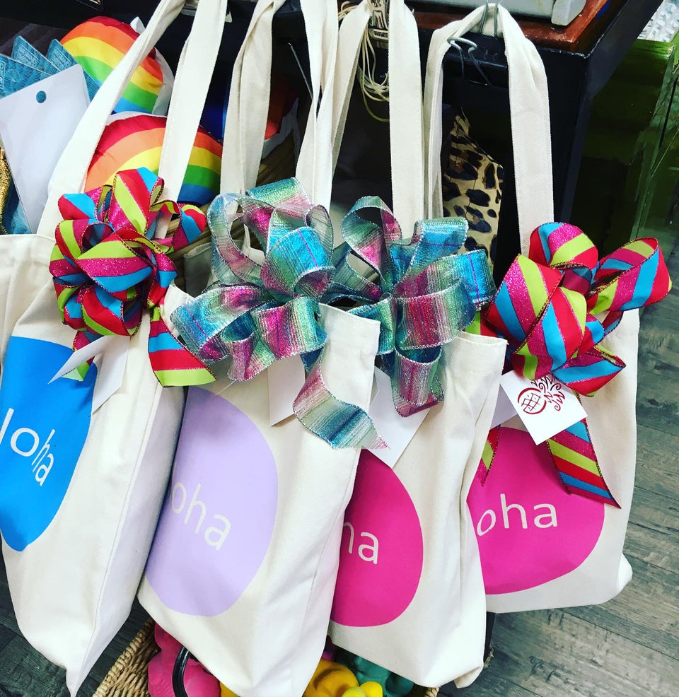 collection of totes that say aloha on the front all with bows