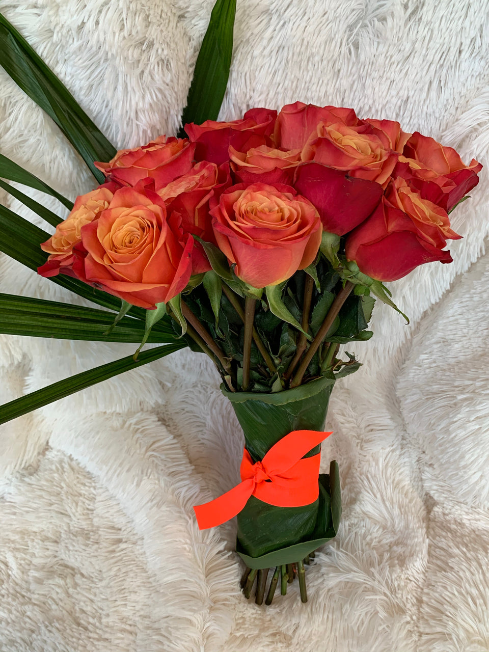orange roses tied together with green leaves