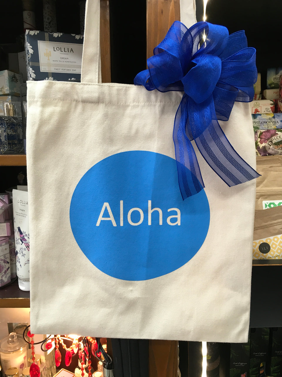 tote with blue circle and aloha written in the middle. blue bow on the side of handle
