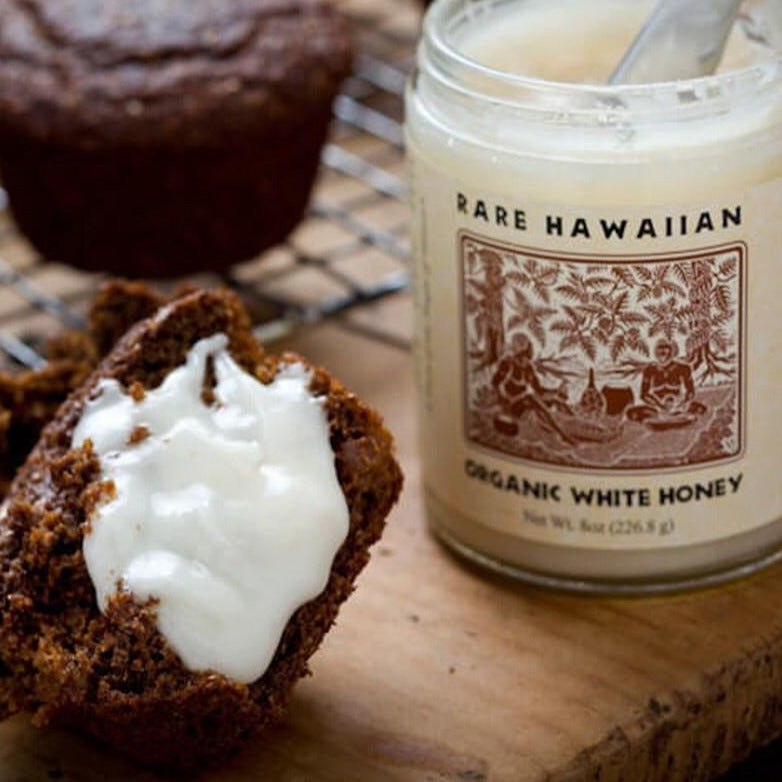 Close up of Organic White honey jar open and some spread on a muffin